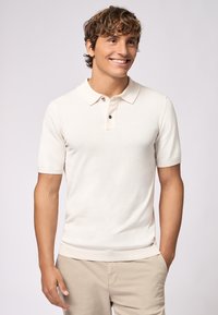 Polo shirt beige chiaro con maniche corte, colletto classico e patta con tre bottoni; realizzato in tessuto a maglia testurizzato.