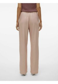 Pantalons larges rose clair avec taille élastique. Texture lisse, design longueur sol. Pas de motifs visibles ni de détails matériels.