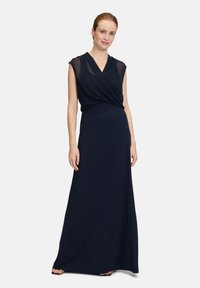 Robe maxi bleu marine avec un devant en portefeuille, manches courtes, tissu léger et texture lisse, adaptée aux occasions formelles.