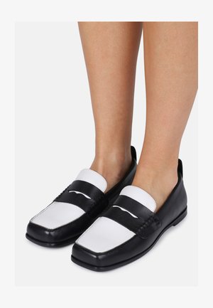 Juodai balti laivai su keturkampiais pirštais, lygia odos apdaila ir kontrastinga juosta per pėdų kraštą. Lygūs padai, minimalus dizainas.