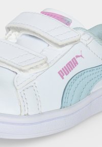 Λευκό αθλητικό παπούτσι Puma με ανοιχτό μπλε και ροζ λεπτομέρειες, δύο λευκές λουρίδες με βέλκρο και ραμμένες λεπτομέρειες.