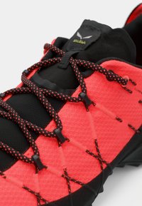 Adidași atletici roșii și negri cu un superior din plasă respirabilă, un sistem de șireturi distinctiv și o talpă din cauciuc texturată pentru aderență.