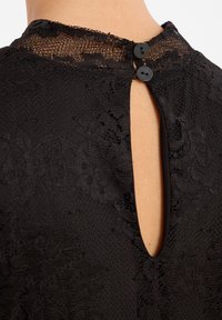 Zwart kanten top met een hoge halslijn, een schone opening aan de achterkant en twee zwarte knopen bij de halslijn, met een gladde textuur.