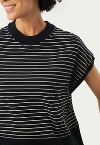 Top de punto a rayas en azul marino y blanco con un cuello redondo y mangas cortas con vuelta. Presenta una textura suave y un ajuste casual.