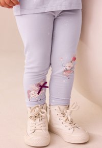 Svetlofialové legíny s rozprávkovým motívom zajaca a jednorožca so sparkly detailmi. Materiál je mäkký a elastický. Kombinované s bielymi teniskami na vysokom podpätku.