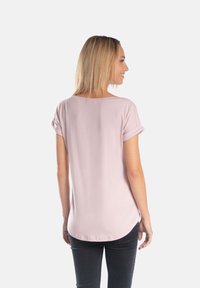 Jasnoróżowa koszula z krótkim rękawem o luźnym kroju i podwiniętych rękawach, z okrągłym dołem i gładką teksturą.