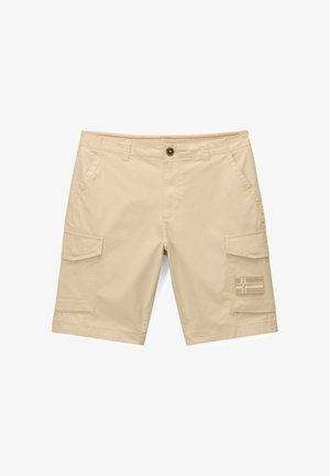 Beżowe szorty cargo z bocznymi kieszeniami na klapę i zapięciem na guzik, z naszywką z motywem krzyża na prawej kieszeni nogawki.