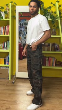 Camo cargobukser med flere lommer, laget av slitesterkt stoff, kombinert med en hvit t-skjorte med rund hals og hvite joggesko.