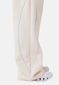 Witte sweatpants met lichtblauwe zijkanten, met een recht model. Draagt met witte, gestructureerde sneakers.