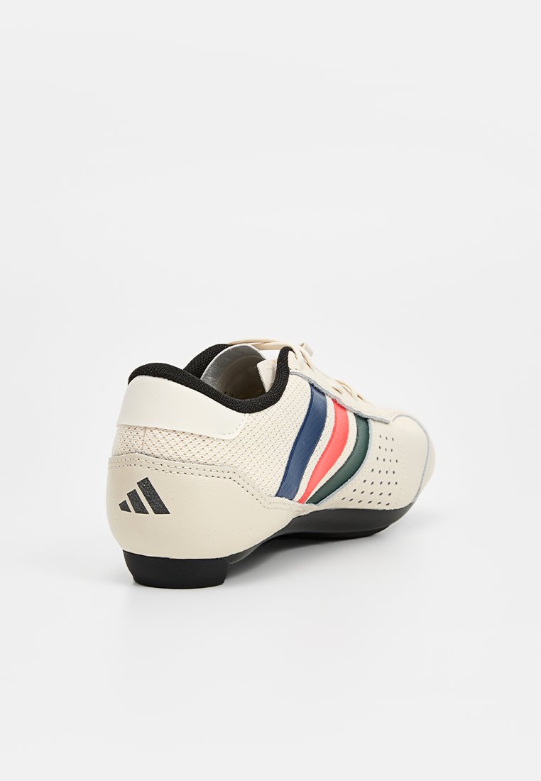 Białe sneakersy z czarną podeszwą, perforowanym noskiem oraz niebieskimi, czerwonymi i zielonymi paskami po bokach, widziane z tylnego prawego kąta.