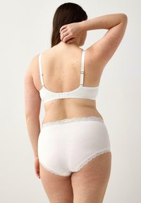 Reggiseno bianco in cotone con spalline regolabili e chiusura a gancio. Mutandine in cotone bianco coordinate con pizzo lungo la vita.