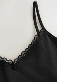 Cămășuță neagră cu bretele subțiri și margine cu dantelă valurată de-a lungul decolteului în V, realizată dintr-un material moale cu textură fină.
