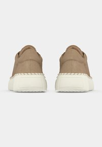 Béžové semišové tenisky s tlustou bílou gumovou podrážkou, vybavené texturovanou patou a minimálním šitím podél okraje podrážky.