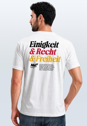 Man with dark hair and beard facing away, wearing white T-shirt with large black, red, and yellow German text on the back.