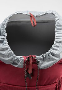 Rode stoffen rugzak met een grijze trekkoordtop, voorzien van een treksluiting en zwarte koorddetails voor aanpassing. Gladde, gestructureerde stof.