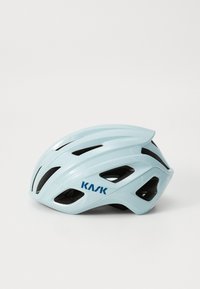 Vaaleansininen KASK-pyöräilykypärä, jossa on tuuletusaukot, lepäämssä valkoisella pinnalla, esitellen sen tyylikästä muotoilua.