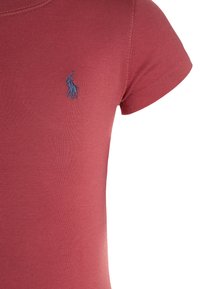 Red fitted t-shirt with short sleeves, ribbed texture, and a small blue embroidered polo logo on the chest.