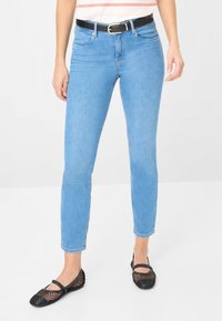 Jean skinny bleu clair en denim avec une taille mi-haute et cinq poches, associés à des ballerines filet noires avec un bout rond et une bride.