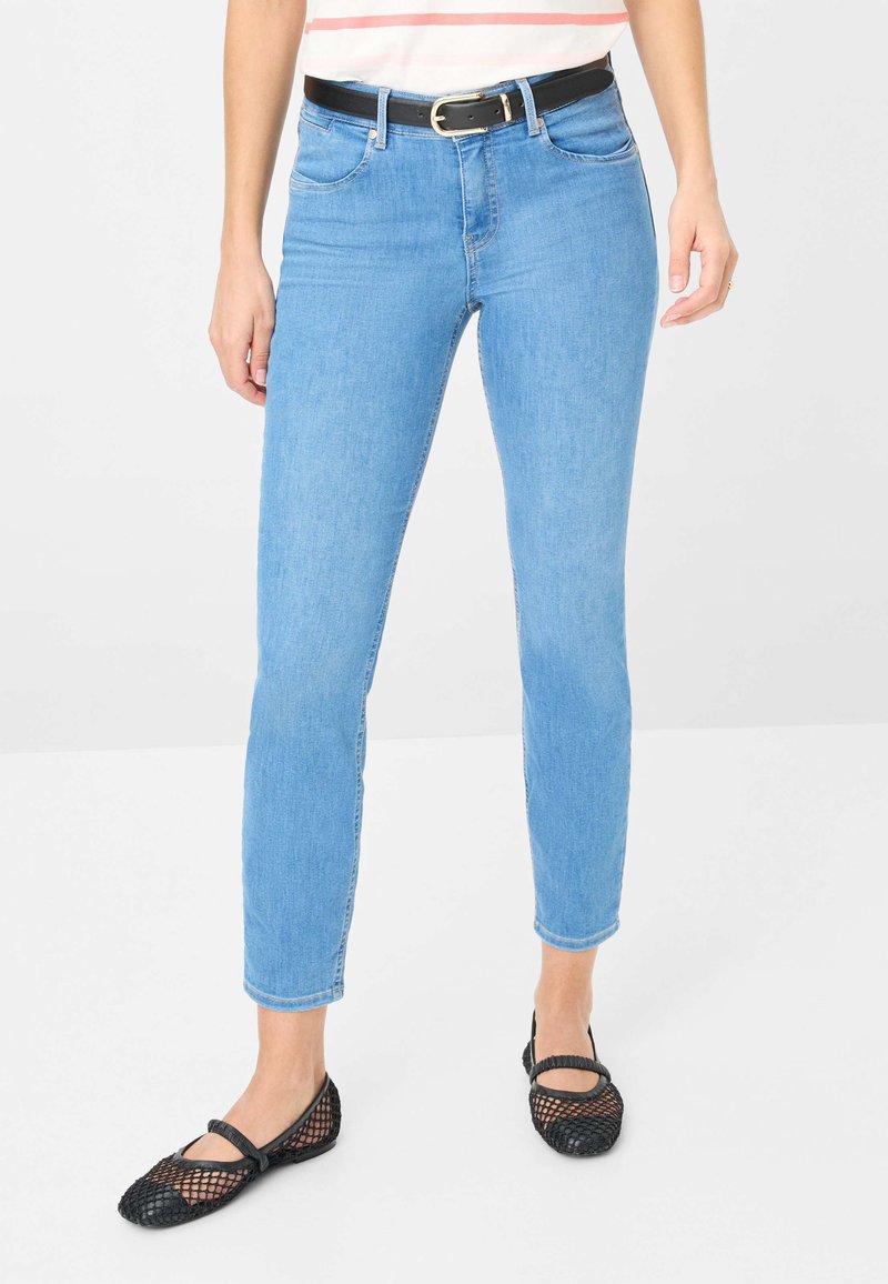 Jean skinny bleu clair en denim avec une taille mi-haute et cinq poches, associés à des ballerines filet noires avec un bout rond et une bride.