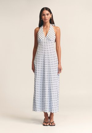 Halterneck-Kleid mit Pünktchenmuster aus hellblauem Stoff, featuring einen tiefen V-Ausschnitt, langer Schnitt und schwarzen runden Mustern auf der gesamten Fläche.