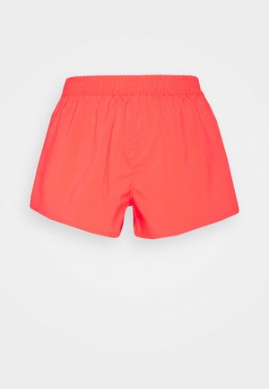 Pantaloncini rosso corallo brillante con vita elastica, vestibilità ampia e tessuto liscio, mostrati da dietro su uno sfondo chiaro e uniforme.