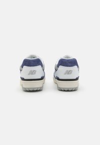 Ténis brancos e azul-marinho com acentos em camurça texturizada, colarinho acolchoado e sola de borracha; apresenta um logo refletivo no calcanhar.