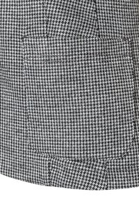 Houndstooth-geweven stof in zwart en wit, met een gestructureerd oppervlak en twee voorzakken.