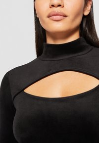 Black, short-sleeve top with a high neckline and cut-out detail below the collarbone. Soft, smooth fabric with a matte finish.