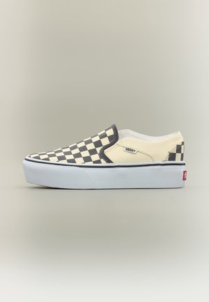 Chaussure basse Vans slip-on avec motif damier noir et beige et semelle blanche épaisse sur fond neutre.