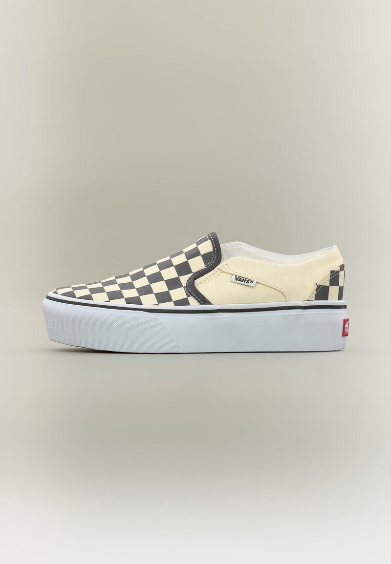 Chaussure basse Vans slip-on avec motif damier noir et beige et semelle blanche épaisse sur fond neutre.