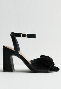 Zwarte fluwelen hoge hakken sandalen met een enkelbandje, voorzien van een gestructureerde bloemenaccent en een chunky hak ontwerp.