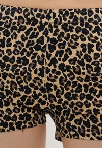 Σορτς με λεοπάρ μοτίβο σε αποχρώσεις καφέ, μαύρου και καφέ, φορεμένα στην πάνω πλευρά των μηρών με ορατές ραφές και ζώνη μέσης.