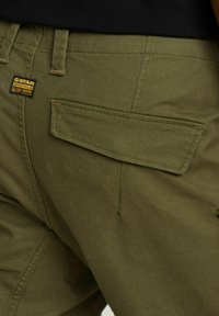 Pantaloni cargo verde oliva con tasca a toppa e etichetta G-Star Originals. Realizzati in un tessuto resistente con dettagli di cucitura visibili.