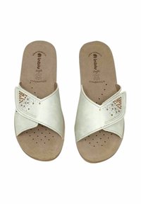 Sandali bianchi con cinghie incrociate e borchie metalliche decorative, realizzati in un materiale simile alla pelle scamosciata, e una soletta imbottita beige con perforazioni.