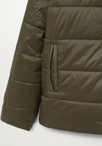 Olive green puffer jacket with quilted texture, featuring a side pocket with a concealed zipper. Smooth, lightweight fabric.