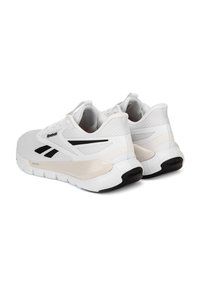 Pár bielych športových topánok Reebok s čiernymi logovými akcentmi a béžovými odpružen�ými medzisúmami zobrazený z bočného zadného uhla.