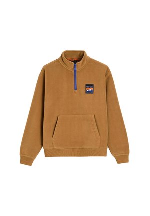 Brązowy polarowy pulower z półzamkiem przy kołnierzu, przednią kieszenią i niebieskim zamkiem błyskawicznym. Ma naszywkę z logo na lewej piersiach. Miękka faktura.