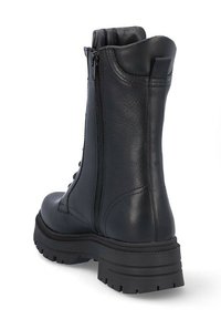 Botas de cuero negras hasta el tobillo con un acabado liso, cordones en la parte delantera, cremallera lateral y suela de goma gruesa para agarre. Diseño robusto y práctico.