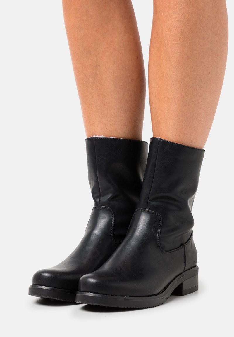 Bottines en cuir noir avec un bout rond, un talon plat et un simple accent de couture. Les bottines présentent un design supérieur légèrement décontracté.