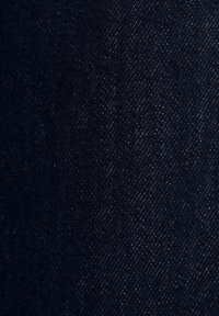 Gros plan sur un tissu en denim bleu foncé montrant une texture de tissage détaillée et un motif de fil diagonal.