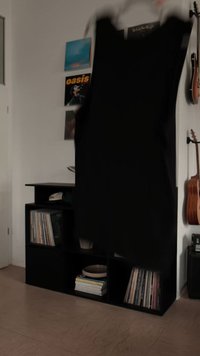 Abito nero senza maniche appeso, realizzato in tessuto liscio, con un design semplice. Aspetto minimalista e leggero.