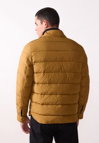 Brown puffer jacket with horizontal quilted pattern, features a collar and side slits, made of smooth, insulated material.