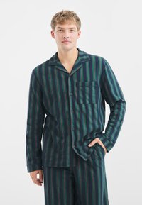 Pánská pruhovaná pyžamová souprava v tmavě zelené a námořnické barvě, s vertikálními pruhy a červenými akcenty, s knoflíkovou košilí a náprsní kapsou.