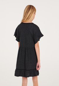 Schwarzes Kurzarmkleid mit gerafftem Saum, das einen taillierten Oberteil und einen lockeren Rock hat. Weicher Stoff mit subtiler Textur.