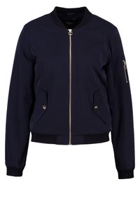 Marinfärgad bomberjacka med dragkedja fram, två sidofickor och en ficka med dragkedja på ärmen. Tillverkad av lätt material med ribbade ärmslut och fåll.