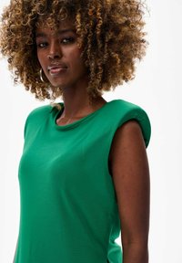 Groene top met korte mouwen, een soepele textuur en een afgerond schouderontwerp. Bevat een ronde hals en subtiele stikseldetails.
