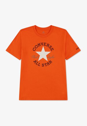 Φωτεινό πορτοκαλί T-shirt με κοντά μανίκια, λευκό αστέρι και μαύρο κείμενο "Converse All Star Chuck Taylor" στο μπροστινό μέρος και μικρό λογότυπο στο μανίκι.