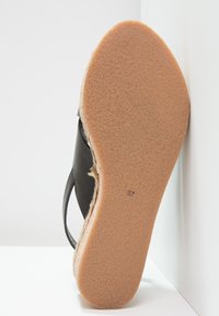 Černá kožená bota s texturovanou, hnědou gumovou podrážkou. Design má zakřivený tvar a viditelné švy podél okraje.