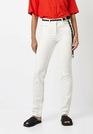 White straight-leg jeans with a braided black belt, paired with a red button-up shirt and black woven slide sandals.