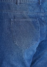 Los jeans de mezclilla azul presentan un bolsillo trasero con un contorno cosido, una textura sutil y un corte recto. La tela parece gruesa y duradera.